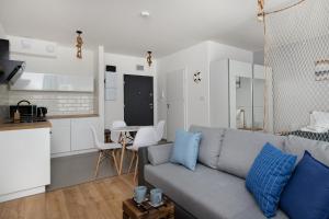 a living room with a gray couch and a kitchen at FALE BAŁTYKU in Gdańsk