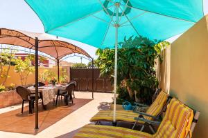 un patio con ombrellone blu, tavolo e sedie di Casa Vacacional Golfin ad Arona