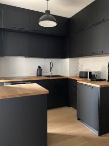 a kitchen with black cabinets and a sink at See & You Ferienwohnung mit Hotelanbindung in Pörtschach am Wörthersee