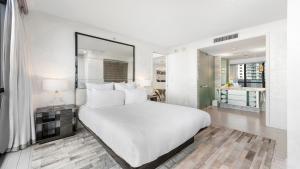 a white bedroom with a large bed and a desk at Private Residence at W South Beach -811 in Miami Beach