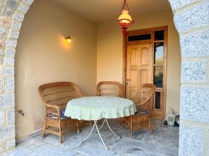 un tavolo con sedie in vimini e un lampadario di Mani family friendly, mountain house with parking a Oitylo