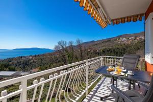 een balkon met een tafel en stoelen en de oceaan bij Apartment Ida with terrace, sea view, near Opatija in Ičići