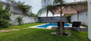 a pool with two chairs and an umbrella in a yard at Casa Jardín Real in Temixco