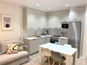a kitchen with a white table and chairs in a room at Malú Playa con Opción de Parking, in Gijón