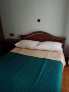 łóżko z drewnianym zagłówkiem i białymi poduszkami w obiekcie VOULA'S HOUSES w mieście Neo Karlowasi