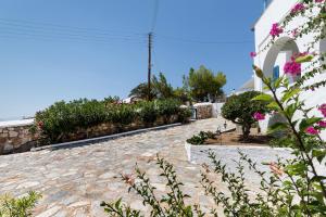 a stone walkway next to a building with flowers at Summer House - Finikas Syros in Víssa