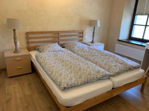 een bed in een slaapkamer met 2 nachtkastjes en 2 lampen bij Les Myosotis in Assesse