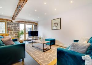 a living room with blue couches and a tv at Derwen in Llanfihangel-geneuʼr-glyn