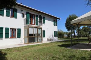 duży biały budynek z zielonymi okiennicami w obiekcie Casa di campagna Cà Teresa w Caorle