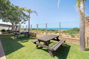 twee picknicktafels op het gras bij de oceaan bij Novobarrosa A in Chiclana de la Frontera