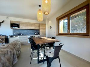 eine Küche und ein Esszimmer mit einem Holztisch und Stühlen in der Unterkunft Alpes Sweet Home - Résidence les Gentianes in L'Alpe-d'Huez