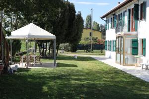 un jardín con una mesa y una sombrilla junto a un edificio en Casa di campagna Cà Teresa en Caorle