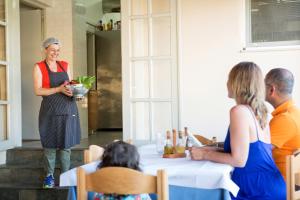 une femme debout à côté d'une table avec un bol de nourriture dans l'établissement Albatross Hotel, à Maleme