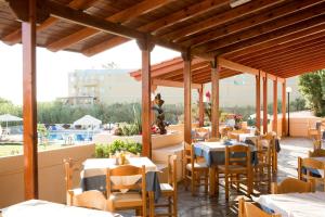 un restaurant avec des tables et des chaises ainsi qu'une piscine dans l'établissement Albatross Hotel, à Maleme