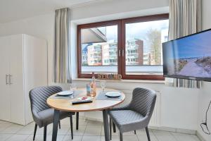 een eetkamer met een tafel en stoelen en een televisie bij Strandburg Strandburg Appartement 1 in Scharbeutz