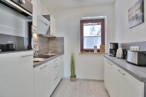 een keuken met witte kasten, een wastafel en een raam bij Strandburg Strandburg Appartement 1 in Scharbeutz