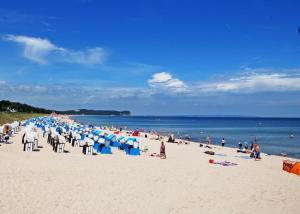 a crowd of people on a beach with blue and white chairs at Appartementhaus mit Balkon im Ostseebad Göhren HS in Göhren