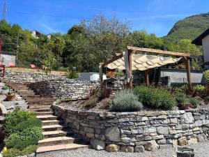 een stenen steunmuur met een stenen trap en een paraplu bij Il Mallo Verde - Lake Como B&B in Mandello del Lario