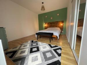 a bedroom with a bed and a green wall at Les gîtes de Madline, Le gîte du prieuré in Saint-Georges-de-Gréhaigne