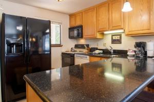 a kitchen with a black refrigerator and wooden cabinets at Beaver Village Unit #0221 in Winter Park
