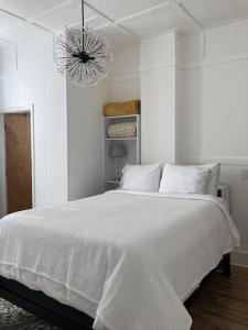 een witte slaapkamer met een wit bed en een kroonluchter bij Walk to Town, Spas, Entertainment! Newly Remodeled, with all amenities in Hot Springs