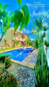 a swimming pool in front of a house with palm trees at Pousada Areias de Flecheiras in Flecheiras