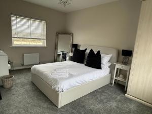 a bedroom with a large white bed with black pillows at High Mill House in Scarborough