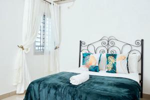 a white bedroom with a large bed with a green blanket at L'IMMEUBLE QUEEN M.N.M in Douala