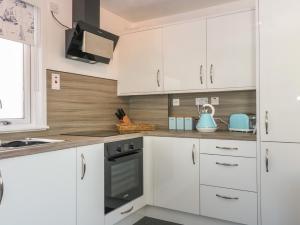 a white kitchen with white cabinets and a stove at Shell Cottage in Peterhead
