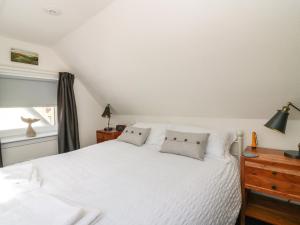 a bedroom with a white bed with two pillows at Shell Cottage in Peterhead