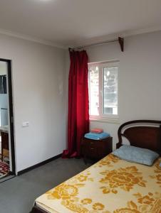 een slaapkamer met een bed en een raam met rode gordijnen bij Grig in Jerevan