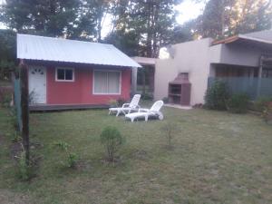 a yard with two white chairs and a house at La Rosadita in Necochea