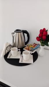 a table with two cups and a tea pot and flowers at Lago d'argento sobe in Veliko Gradište