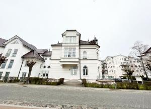 una gran casa blanca en una calle de la ciudad en Schloss Hohenzollern - Wohnung 14, en Ahlbeck