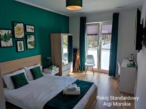 ein Schlafzimmer mit einem Bett und einer grünen Wand in der Unterkunft BALTICUS Mrzeżyno in Mrzeżyno