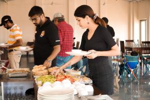 une femme tenant une assiette de nourriture sous forme de buffet dans l'établissement Jawai Empire Resort by Premier Hotels, à Pāli