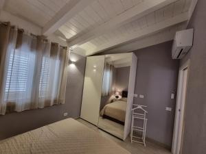 Dormitorio pequeño con cama y espejo en Appartamento Spargi en Isola Rossa