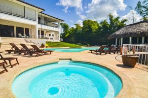 einen Pool mit Stühlen und ein Haus in der Unterkunft Six Bedrooms Luxury Disco Room Villa in La Romana