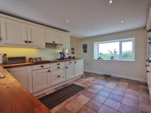 a kitchen with white cabinets and a window at Tan Y Ffordd in Morfa Nefyn