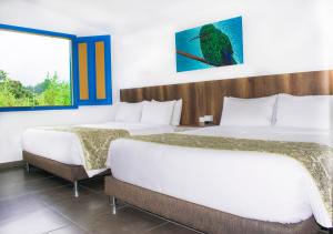 a hotel room with two beds and a window at Hotel Hacienda Santa Clara in Santa Rosa de Cabal