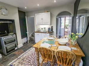 a kitchen with a wooden table with chairs and a stove at Dobbies Den in Bewdley