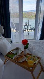 un vassoio di cibo su un letto accanto a una finestra di Lago d'argento sobe a Veliko Gradište