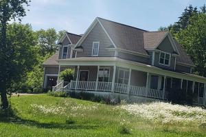 a house with a large yard with white flowers at Front of Country shabby chic Home near Ganondagan Historic Site on 10 wooded acres in Victor