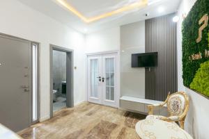 a bathroom with a toilet and a tv on a wall at Phoenix Luxury Apartments in Abuja