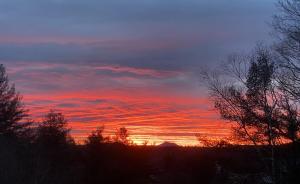 um pôr-do-sol com árvores e nuvens no céu em Artful Lodging & Retreats em Montpelier