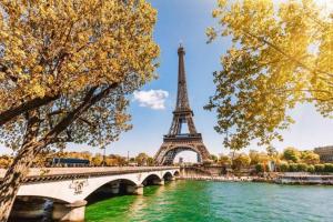 uma ponte sobre um rio com a torre Eiffel em L'Olivier Disneyland JO Paris 2024 avec Parking em Bailly-Romainvilliers
