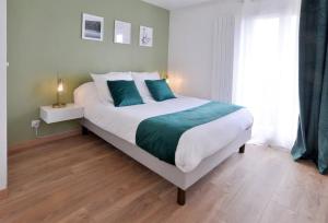 Un dormitorio con una gran cama blanca con almohadas azules. en L'Olivier Centre ville Parking Disneyland 4 personnes et 1 bébé, en Bailly-Romainvilliers