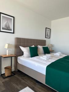 Un dormitorio con una cama grande con almohadas verdes y blancas en Weitblick - mit Strandkorb, mehr Meer geht nicht, en Glücksburg