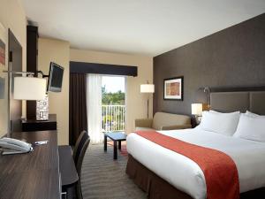 a hotel room with a bed and a desk at Holiday Inn Express & Suites Naples Downtown - 5th Avenue by IHG in Naples