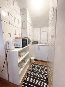 a small white kitchen with a microwave and a sink at Jenny's Apartment in Mostar